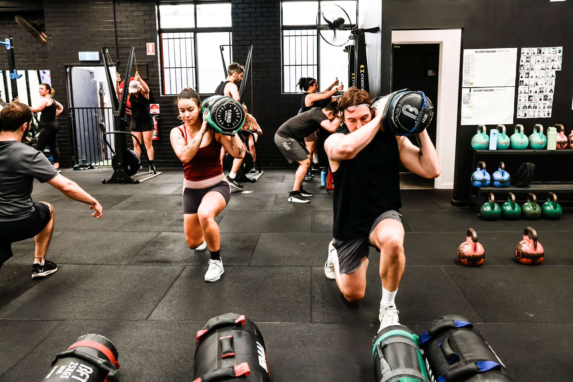 Members carrying weighted sandbags through a lunge circuit at BFT Abbotsford